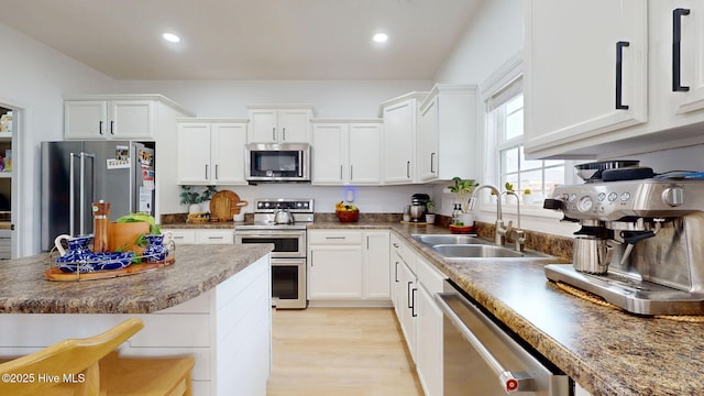 kitchen featuring light wood finished floors, white cabinets, appliances with stainless steel finishes, and a sink