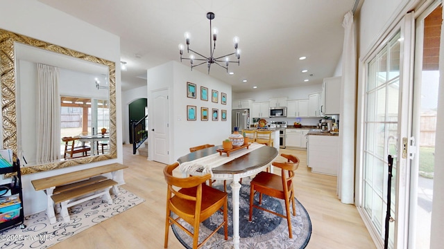 dining area featuring recessed lighting, a notable chandelier, light wood-style floors, and arched walkways