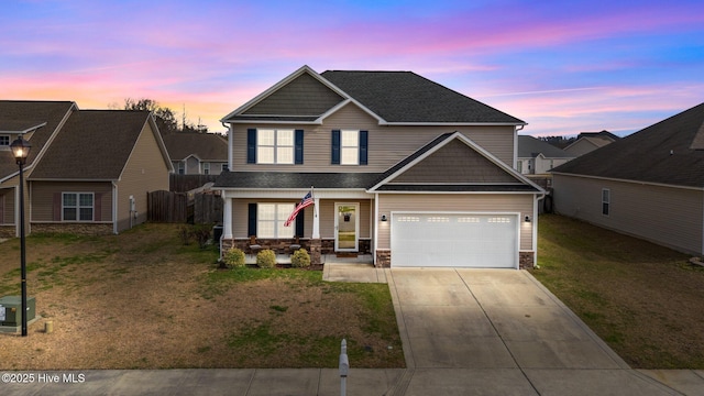 craftsman house featuring fence, roof with shingles, concrete driveway, stone siding, and a lawn