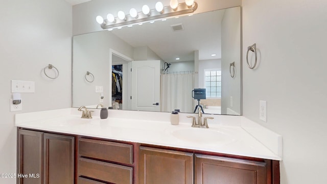 bathroom featuring a shower with shower curtain, double vanity, visible vents, and a sink