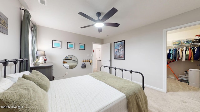 bedroom featuring a walk in closet, a ceiling fan, a closet, baseboards, and light colored carpet