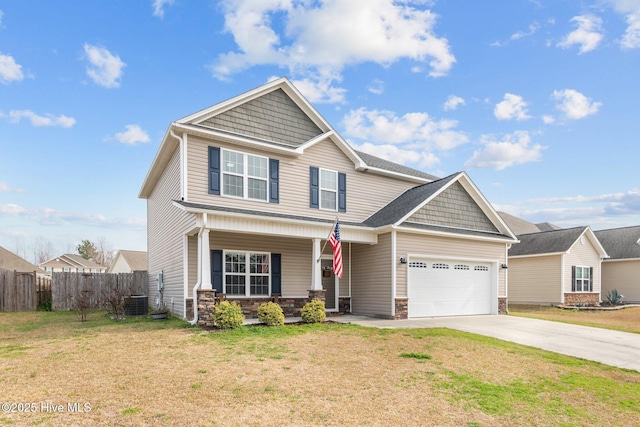 craftsman house with a front lawn, fence, stone siding, and driveway