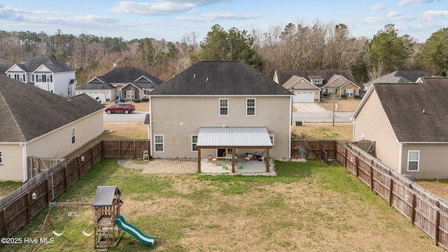 rear view of house with a patio, a playground, a yard, and a fenced backyard