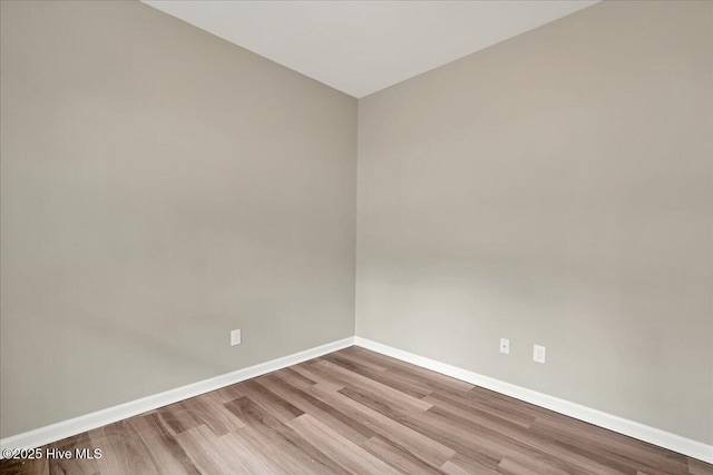 spare room featuring baseboards and wood finished floors