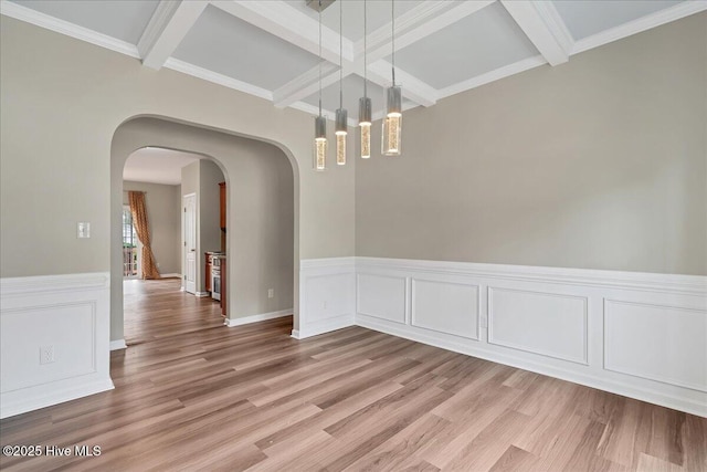 unfurnished dining area with beam ceiling, arched walkways, light wood-type flooring, and coffered ceiling