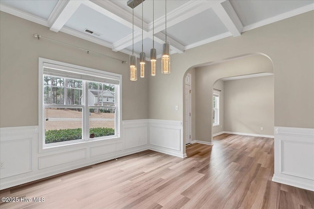 unfurnished dining area featuring a wealth of natural light, beam ceiling, arched walkways, and light wood-type flooring