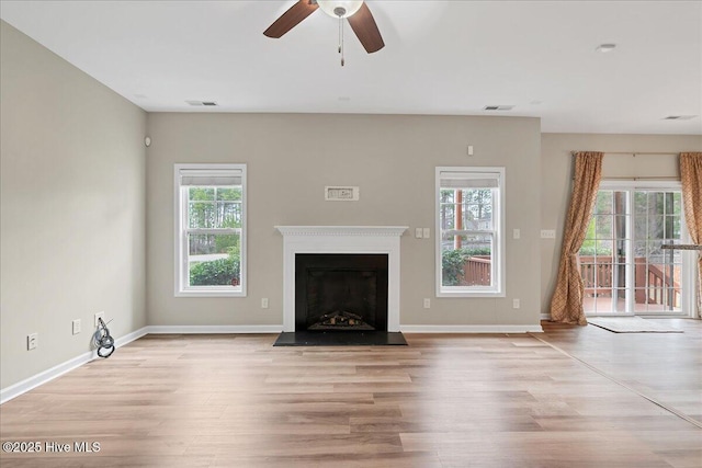 unfurnished living room with a healthy amount of sunlight, wood finished floors, and a fireplace