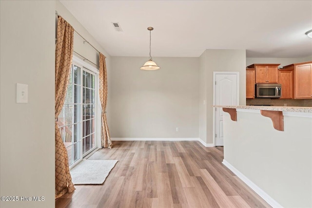 unfurnished dining area with visible vents, baseboards, and light wood finished floors