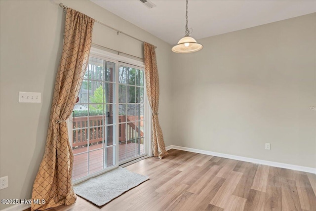 unfurnished dining area featuring visible vents, light wood-style floors, and baseboards