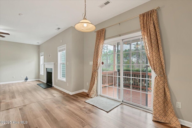 unfurnished living room featuring visible vents, a healthy amount of sunlight, and wood finished floors