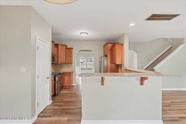 kitchen with tasteful backsplash, visible vents, a breakfast bar, appliances with stainless steel finishes, and arched walkways