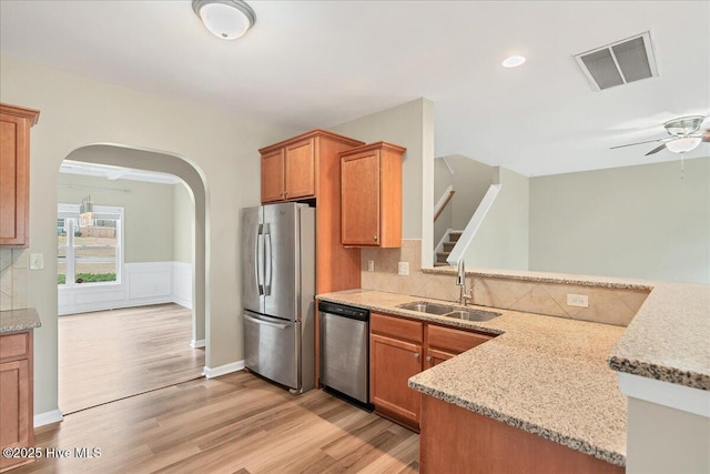 kitchen with visible vents, backsplash, light wood-type flooring, appliances with stainless steel finishes, and a sink