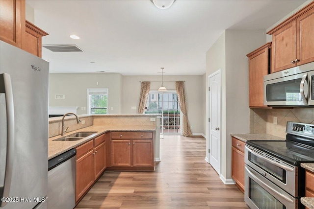 kitchen with tasteful backsplash, visible vents, light wood-style flooring, appliances with stainless steel finishes, and a sink