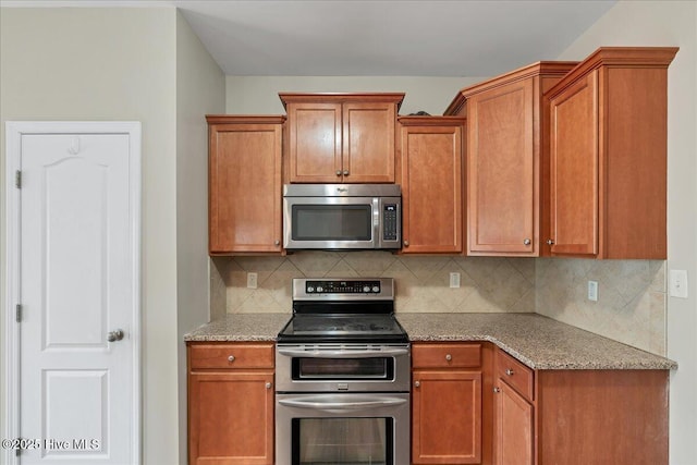 kitchen with light stone counters, brown cabinetry, tasteful backsplash, and appliances with stainless steel finishes