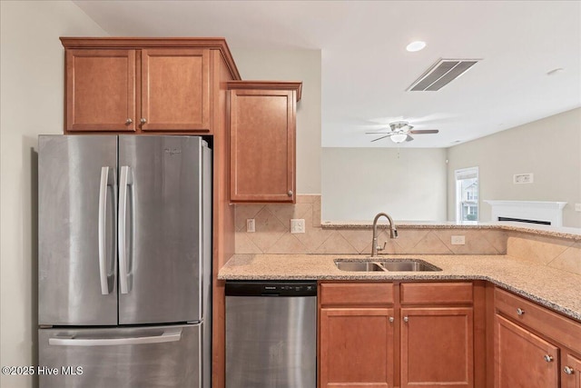 kitchen featuring visible vents, decorative backsplash, brown cabinets, appliances with stainless steel finishes, and a sink