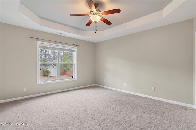 unfurnished room with baseboards, a raised ceiling, carpet, and visible vents