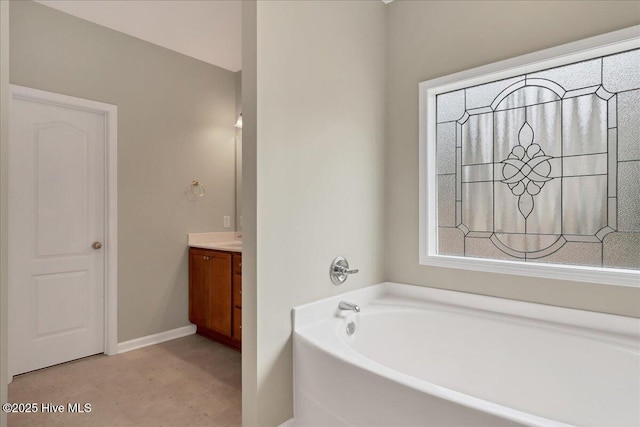 full bathroom featuring baseboards, a bath, and vanity