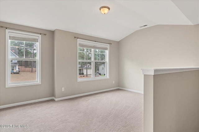 spare room with visible vents, carpet floors, a healthy amount of sunlight, and vaulted ceiling