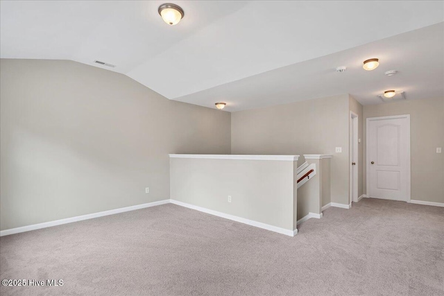 spare room featuring baseboards, light carpet, lofted ceiling, and visible vents