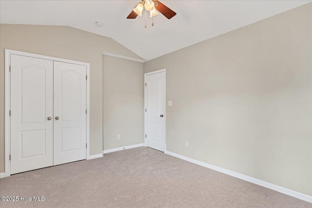 unfurnished bedroom with a closet, baseboards, carpet, and lofted ceiling