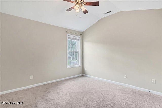 carpeted spare room with visible vents, lofted ceiling, baseboards, and a ceiling fan