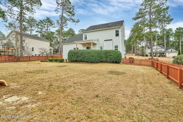 rear view of property featuring a yard and fence