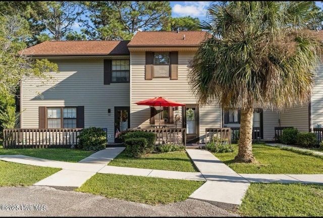 multi unit property with covered porch, a shingled roof, and a front yard