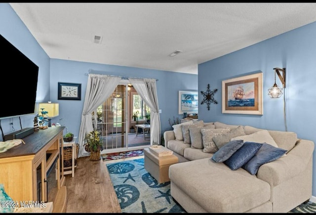 living area with visible vents, a textured ceiling, and wood finished floors