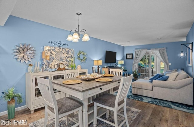 dining space with a notable chandelier, baseboards, and wood finished floors