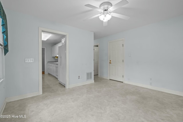 unfurnished bedroom featuring baseboards, visible vents, freestanding refrigerator, ceiling fan, and ensuite bathroom