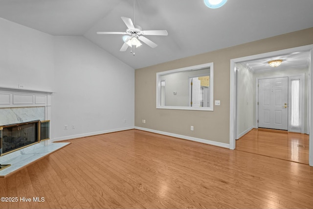 unfurnished living room featuring a fireplace, baseboards, light wood-style floors, and vaulted ceiling