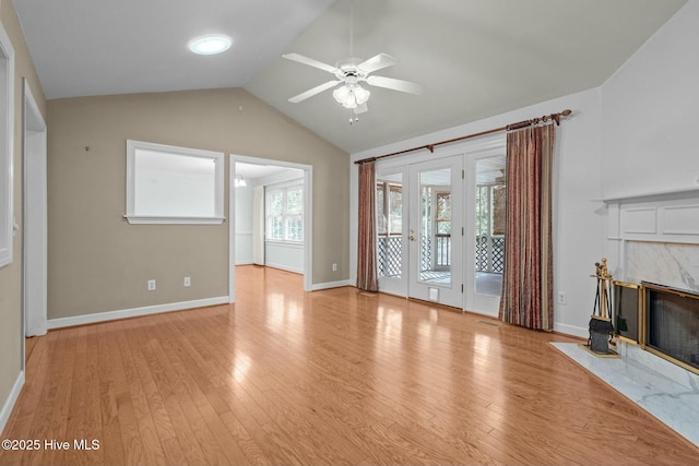 unfurnished living room with a ceiling fan, light wood-style flooring, a high end fireplace, and vaulted ceiling