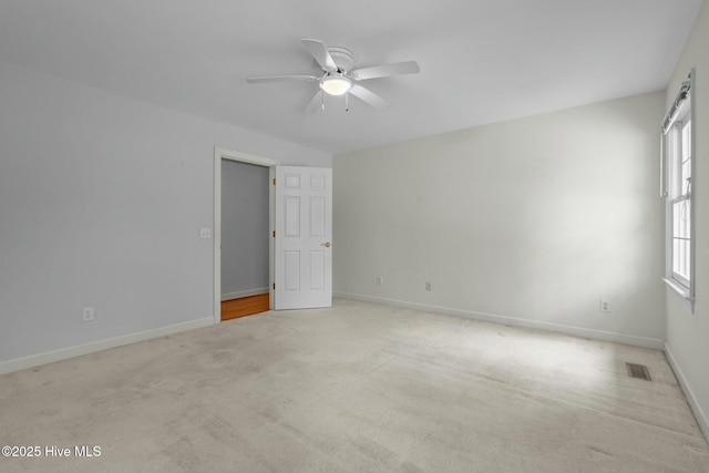 carpeted empty room featuring baseboards, visible vents, and ceiling fan