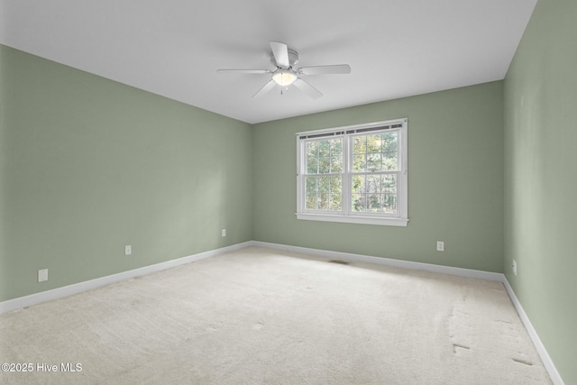 spare room with visible vents, light colored carpet, baseboards, and ceiling fan