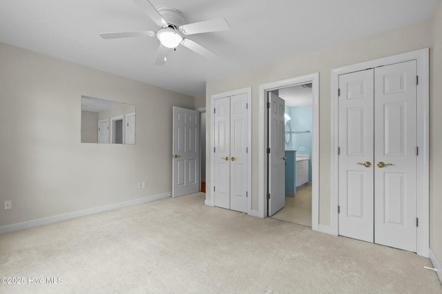 unfurnished bedroom featuring two closets, ensuite bathroom, baseboards, and carpet floors