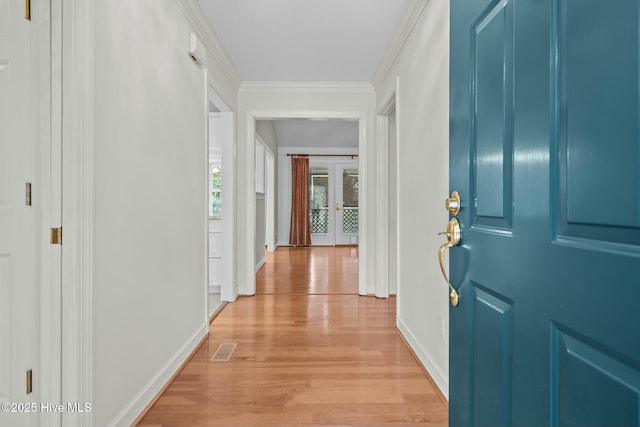 entryway with visible vents, baseboards, crown molding, and light wood finished floors