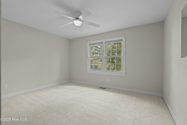 carpeted empty room featuring visible vents, ceiling fan, and baseboards