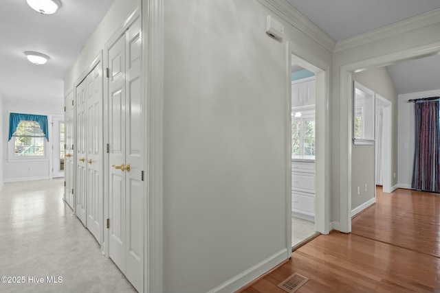 corridor featuring visible vents, baseboards, a healthy amount of sunlight, and light wood-style flooring