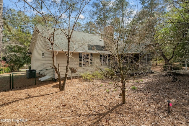 back of property with a gate, central AC, a chimney, and fence