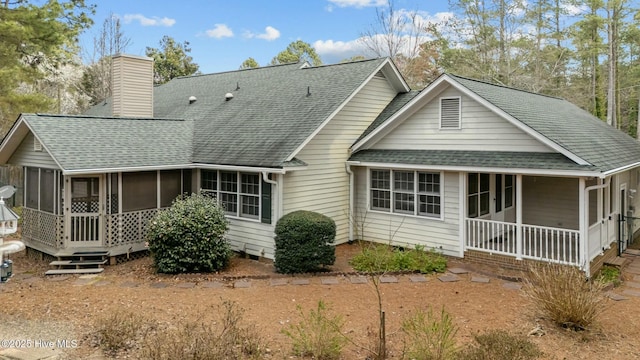 rear view of property with a shingled roof, a porch, a chimney, and a sunroom