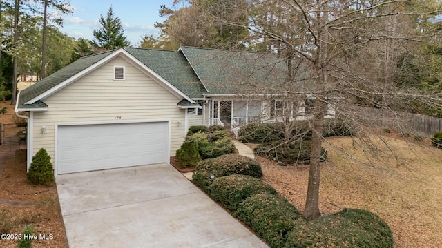 single story home with driveway, a shingled roof, and an attached garage