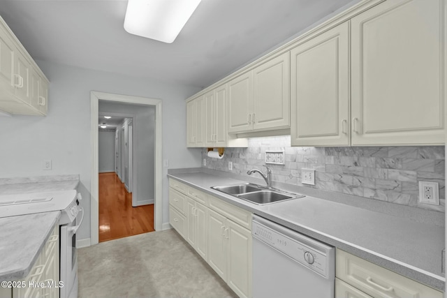 kitchen with baseboards, light countertops, decorative backsplash, white appliances, and a sink