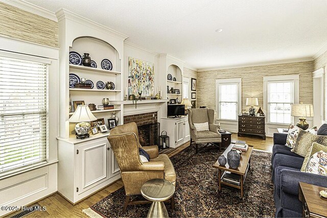 living room featuring a fireplace, light wood-type flooring, and ornamental molding