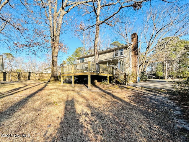 back of house with a wooden deck, fence, a chimney, and stairway