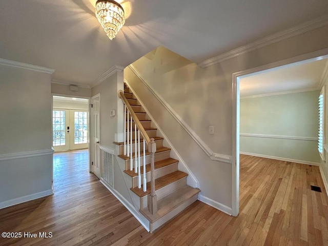 staircase with french doors, crown molding, baseboards, and wood finished floors