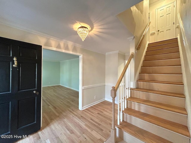 staircase featuring wood finished floors, baseboards, and ornamental molding