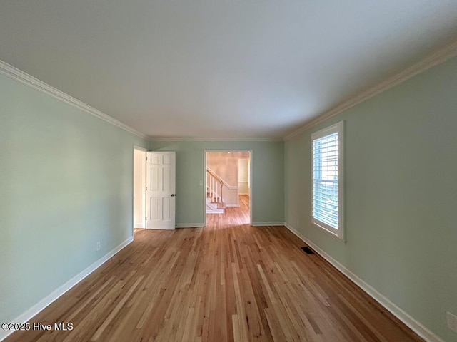 spare room with visible vents, wood finished floors, stairway, crown molding, and baseboards