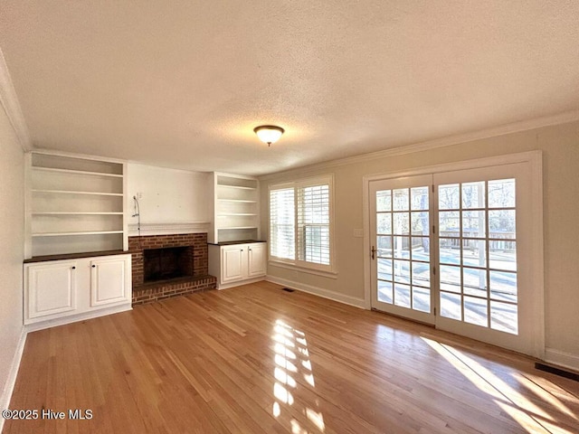 unfurnished living room with crown molding, a brick fireplace, wood finished floors, and a textured ceiling