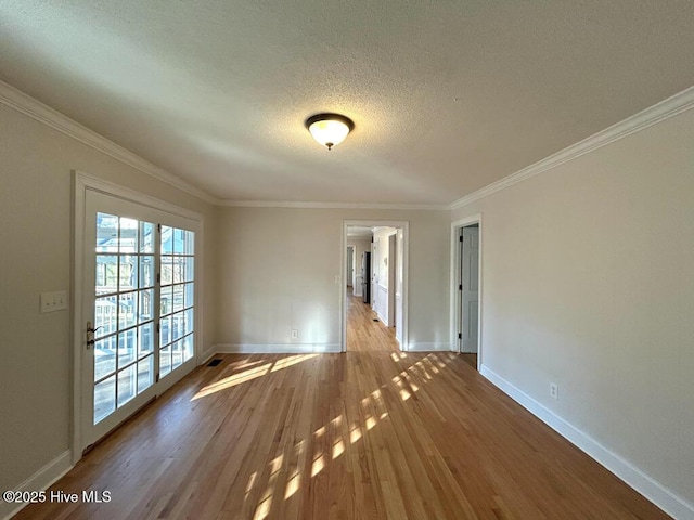 unfurnished room featuring a textured ceiling, crown molding, baseboards, and wood finished floors