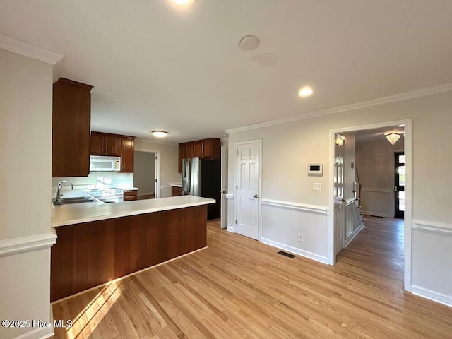 kitchen featuring a sink, white appliances, ornamental molding, and light countertops